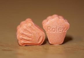 oranje pillen met mdma extase dope rolex drug dichtbij omhoog achtergrond prima kunst in hoog kwaliteit afdrukken foto