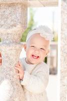 portret van een glimlachen weinig blond meisje met kort haar, met een bloem hoofdband. schattig en glimlachen weinig meisje Aan de straat. foto