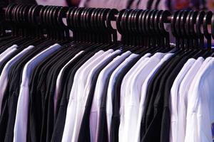meerdere wit en zwart overhemden hangende Aan een Kledinglijn. foto