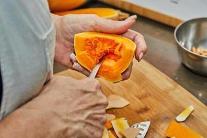 chef bezuinigingen pompoen in de vorm van Peer Aan houten bord in de huis keuken foto