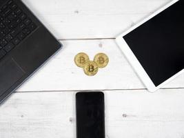 gouden bitcoin Aan de bureau met laptop tablet en smartphone in de omgeving van top visie de digitaal geld crypto concept foto