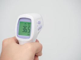 hand- Holding infrarood thermometer digitaal Bij wit achtergrond foto