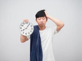 Aziatisch slaperig Mens met handdoek Holding klok in hand- laat concept wit achtergrond foto