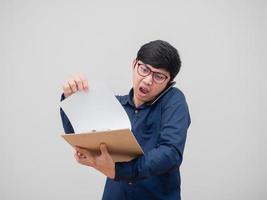 Aziatisch Mens bezig pratend met mobiel telefoon en vinden document bord in hand- wit achtergrond foto