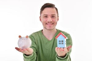 Mens Holding een varkentje bank en een huis model. behuizing industrie hypotheek plan en woon- belasting besparing strategie foto