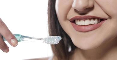 portret van aantrekkelijk glimlachen vrouw geïsoleerd Aan wit studio schot poetsen haar tanden foto