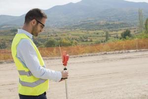 landmeter ingenieur is meten niveau Aan bouw plaats. landmeters ervoor zorgen nauwkeurig metingen voordat onderneming groot bouw projecten. foto