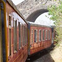 speelgoedtrein die zich op berghellingen beweegt, prachtig uitzicht, een zijberg, een zijvallei die zich op een spoorlijn naar de heuvel beweegt, tussen groen natuurlijk bos. speelgoedtrein van kalka naar shimla in india, indiase trein foto