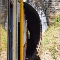 speelgoedtrein die zich op berghellingen beweegt, prachtig uitzicht, een zijberg, een zijvallei die zich op een spoorlijn naar de heuvel beweegt, tussen groen natuurlijk bos. speelgoedtrein van kalka naar shimla in india, indiase trein foto