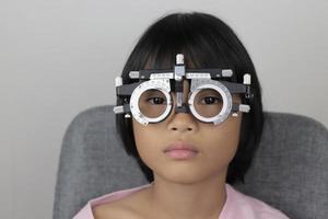 meisje oog test concept, kind vervelend beproeving kader bril, oog test concept foto