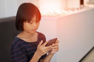 weinig meisje zittend Aan de telefoon foto