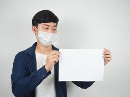 Aziatisch Mens met masker beschermen op zoek Bij blanco papier in zijn hand- Aan wit achtergrond foto