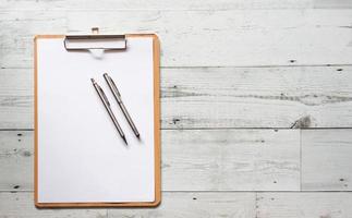 twee zilver pen Aan blanco wit document vel Aan hout klembord Aan wit hout tafel top visie ruimte foto