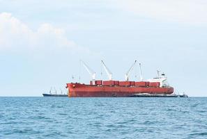 groot schip rood kleur met groot kraan in de oceaan landschap, industrieel boot in de zee logistiek concept foto