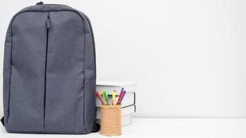 school- zak met potlood doos en boeken Aan de bureau wit achtergrond kopiëren ruimte foto