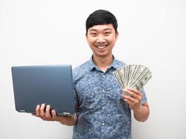 Mens blauw overhemd Holding laptop met een veel van geld glimlachen geïsoleerd foto