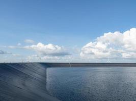 reservoir Aan de berg landschap met wind turbine en bewolkt Aan blauw hemel, water in reservoir foto