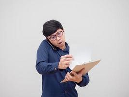 Aziatisch Mens bezig pratend met mobiel telefoon en vinden document bord in hand- wit achtergrond foto