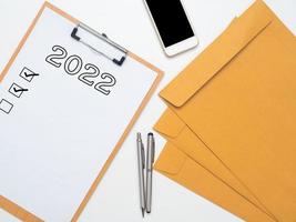 werkplaats top visie 2022 en controleren lijst, document mobiel telefoon pen en envelop Aan tafel foto