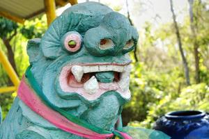 een oud groen Chinese leeuw standbeeld gebonden met een driekleur boog Aan de borst.zijn Chinese naam is gebeld elfje of pi ja. foto