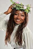 portret van een jong Afrikaanse Amerikaans vrouw , model- van mode, met groot bloemen in haar haar- foto