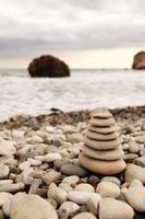 piramide stenen aan de kust op een zonnige dag op de achtergrond van de blauwe zee. fijne vakantie. kiezelstrand, kalme zee, reisbestemming. concept van gelukkige vakantie aan zee. foto