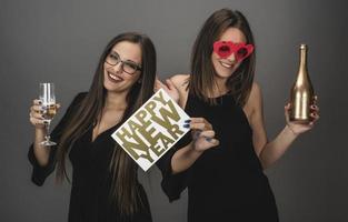 twee vrouw vrienden vieren nieuw jaar met confetti en Champagne Holding teken. geïsoleerd foto