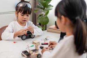 azië studenten leren thuis in het coderen van robotauto's en elektronische bordkabels in stam, stoom, wiskunde engineering wetenschap technologie computercode in robotica voor kinderen concept. foto