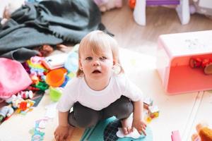 schattig grappig baby meisje zittend Aan verdieping in kinderen kamer Bij huis foto