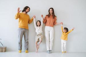 jong gelukkig familie met twee kinderen meisjes Aan achtergrond van grijs muur foto