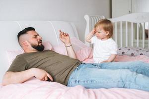 streng vader jong Mens en baby meisje weinig dochter Aan bed in kamer Bij huis foto