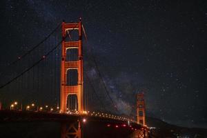 verlichte gouden poort suspensie brug onder mooi ster veld- Bij nacht foto