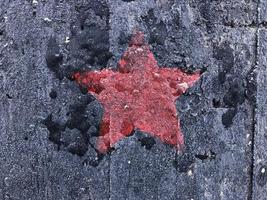 rood vijfpuntig ster Aan een zwart haveloos achtergrond foto