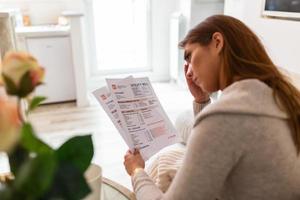 binnen- schot van terloops gekleed jong vrouw Holding papieren in haar handen, berekenen familie begroting, proberen naar opslaan sommige geld , hebben benadrukt en geconcentreerd kijken foto