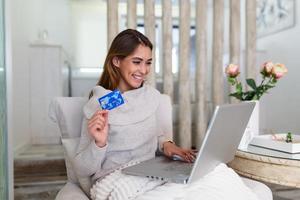 afbeelding tonen mooi vrouw boodschappen doen online met credit kaart. vrouw Holding credit kaart en gebruik makend van laptop. online boodschappen doen concept foto