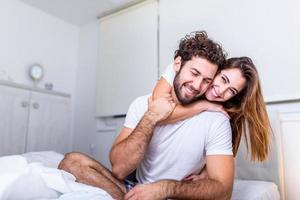 mooi jong paar Bij huis. knuffelen, zoenen en genieten van uitgeven tijd samen. gepassioneerd mooi paar in slaapkamer genieten van voorspel foto