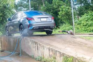 personeel of auto wasmachine Bij auto zorg onderhoud centrum het wassen een auto van klant door gebruik makend van hoge druk water geweer foto