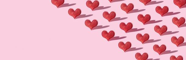 patroon met rood schitteren hart vorm Aan roze achtergrond met moeilijk schaduw. valentijnsdag dag minimalistisch symbool liefde. banier foto