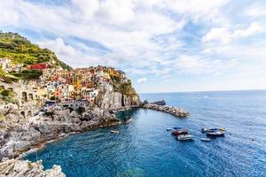 cinque terrein, Italië juli 18, 2019 klassiek visie van manarola - kleurrijk huizen in een dramatisch klif rots vorming in de buurt de zee met een visvangst natuurlijk haven foto