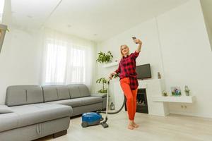 vrouw schoonmaak verdieping vacuüm schoonmaakster in de modern wit leven kamer foto