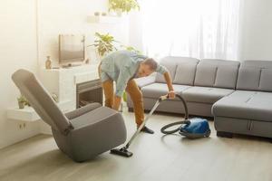 coronavirus pandemie. een Mens met een vacuüm schoonmaakster in zijn appartement. huis kantoor. quarantaine. afgelegen werk. een Mens in een bedrijf overhemd en onderbroek houdt. foto