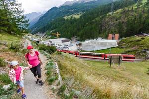 wandelaars met rugzak op zoek Bij bergen, alpine visie, moeder met kind foto