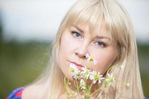 portret van een middelbare leeftijd vrouw met wit haar- Holding een boeket van veld- madeliefjes. foto