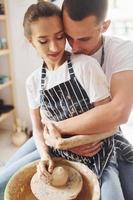 met haar vriendje of echtgenoot. jong vrouw keramist binnenshuis met handgemaakt klei Product. opvatting van pottenbakkerij foto