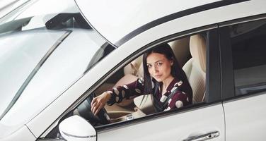 kant visie van mooi jong brunette dat binnen van modern auto. rijden auto foto