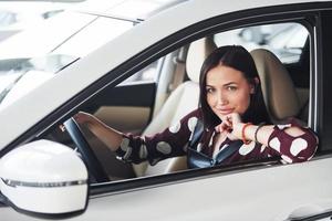 kant visie van mooi jong brunette dat binnen van modern auto. rijden auto foto