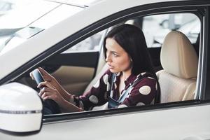 kant visie van mooi jong brunette dat binnen van modern auto. rijden auto foto