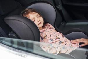 schattig weinig meisje slapen binnen van de auto. opvatting van op reis en vakantie foto