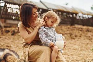 vers natuurlijk melk. jong moeder met haar dochter is Aan de boerderij Bij zomertijd foto