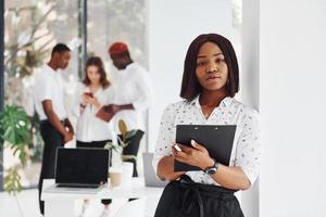 vrouw Holding kladblok. groep van Afrikaanse Amerikaans bedrijf mensen werken in kantoor samen foto